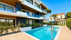 A modern residential building with a swimming pool, balconies, and a garden area. - Aurora Sand 2 - Carraro immobiliare Jesolo (Lido di Jesolo)