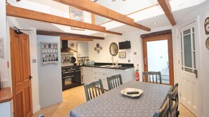 A kitchen with a dining table, chairs, and a view of the outside. - Unique town house with games room (Padstow)