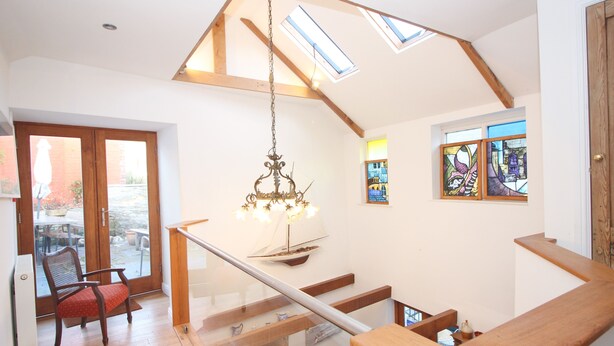 A spacious room with a wooden staircase, a chandelier, and a view of the outside. - Unique town house with games room (Padstow)