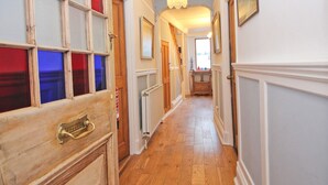 A hallway with wooden floors, a radiator, and a door with a brass handle. - Unique town house with games room (Padstow)