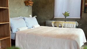 A bedroom with a large bed, a wooden wardrobe, a desk, and a potted plant. - Balay Yuhom (General Luna)