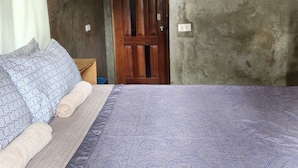 A bedroom with a large bed, a wooden door, and a framed picture on the wall. - Balay Yuhom (General Luna)
