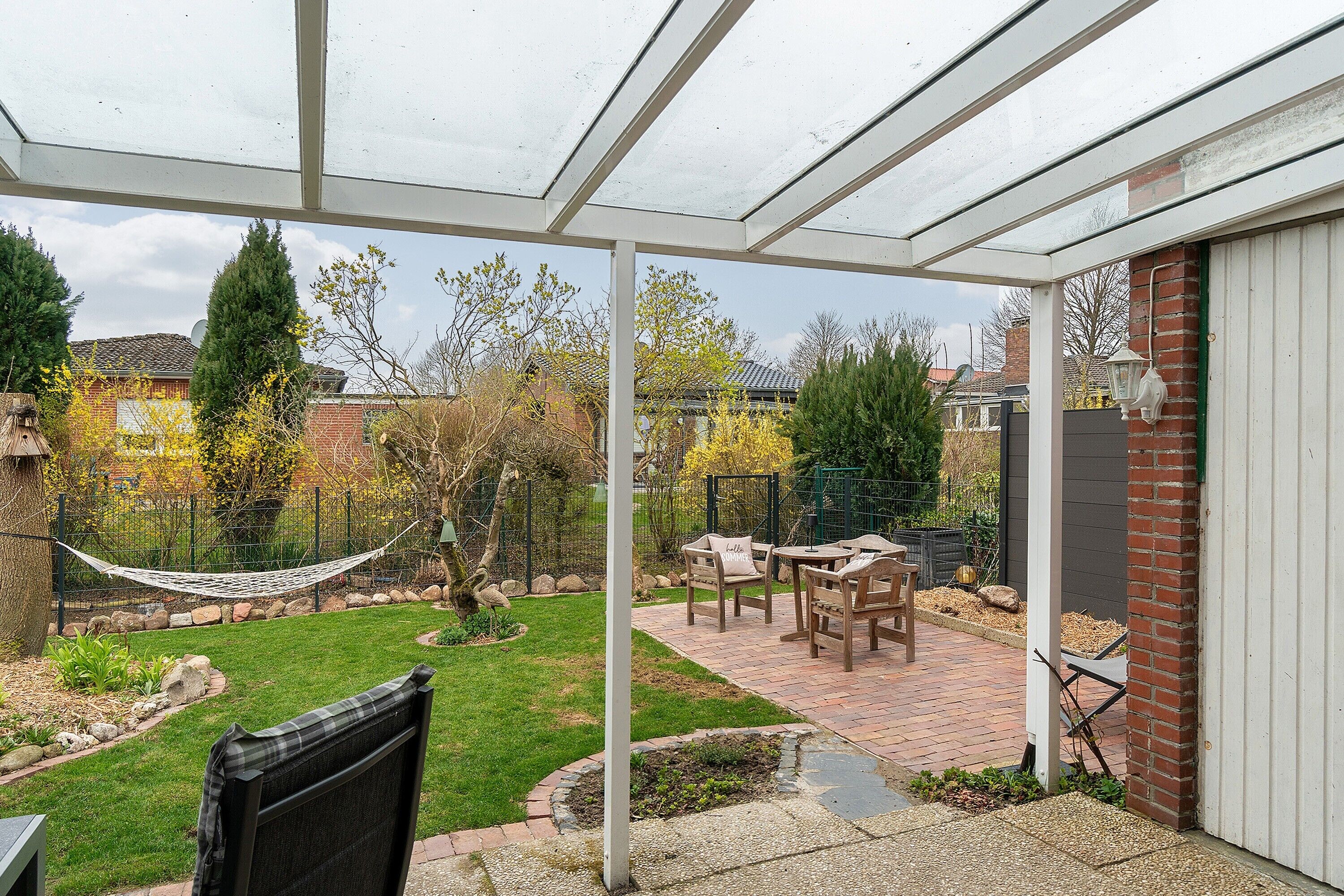 A covered patio with a brick pathway, a hammock, and outdoor furniture. - Holiday home 'Me(e)rzeit' in Schillig (Schillig)