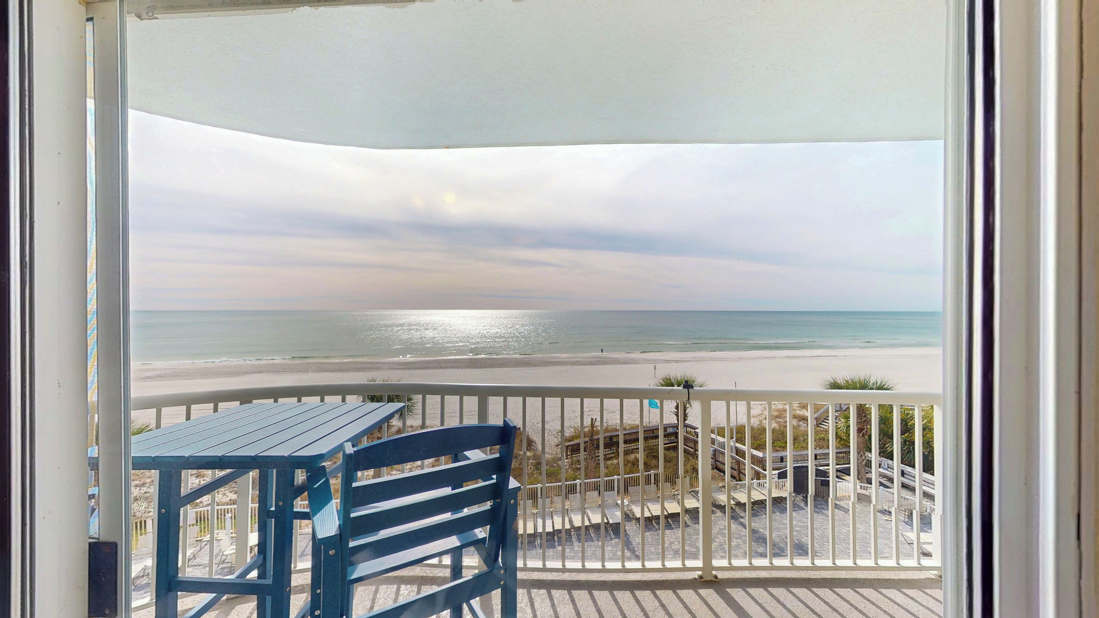 A balcony with a view of the beach and ocean.