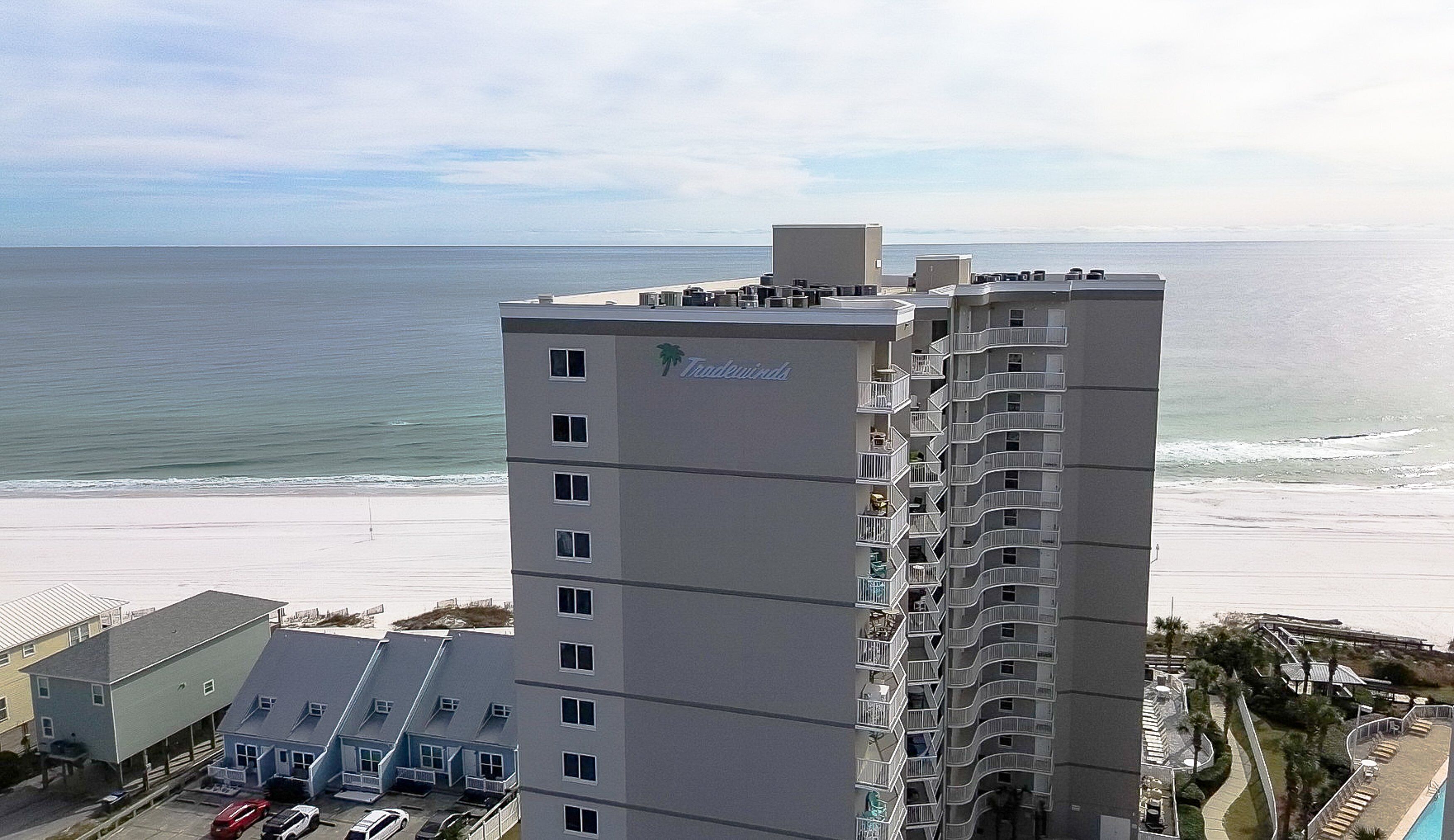 A high-rise hotel with balconies overlooking a beach.