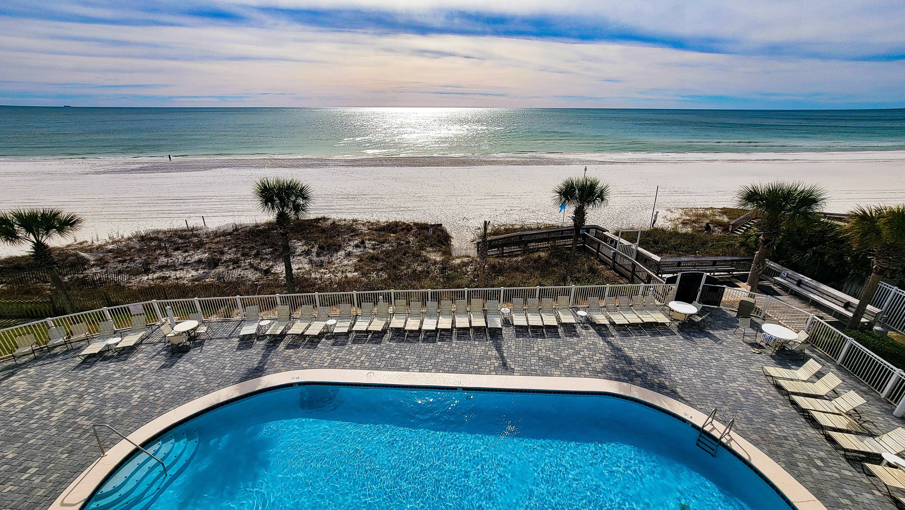 A pool area with a view of the beach and ocean.