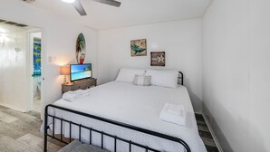 Camera da letto con un letto, una ventola a soffitto, una TV e opere d'arte alle pareti.
