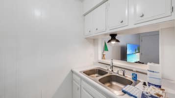 A kitchen with white cabinets, a double sink, and a countertop with a dish sponge and soap dispenser.