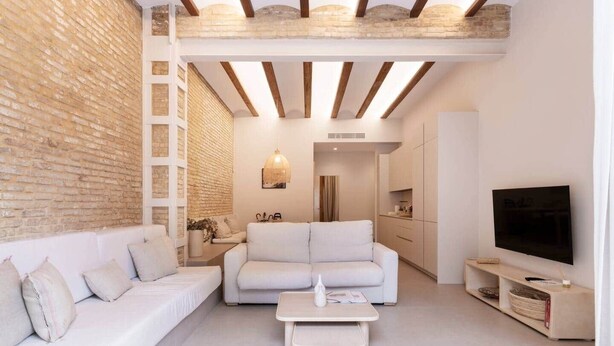Uma sala de estar moderna com um sofá branco, uma mesa de centro e uma TV.