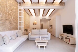 A modern living room with a white sofa, a coffee table, and a TV. - Oasis in Cabañal 2 (Valencia)