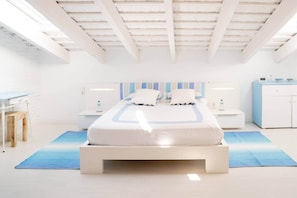 Ein modernes Schlafzimmer mit einem großen Bett, Nachttischen, einem Schreibtisch und einem Kleiderschrank.