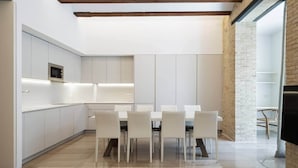 Una cocina moderna con armarios blancos, microondas integrado y un comedor con mesa y sillas.