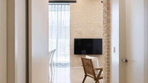 Un pasillo con suelo de baldosas, pared de ladrillo y un televisor de pantalla plana montado.