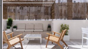 Un patio con un sofá, dos sillas de madera y una mesa de centro.
