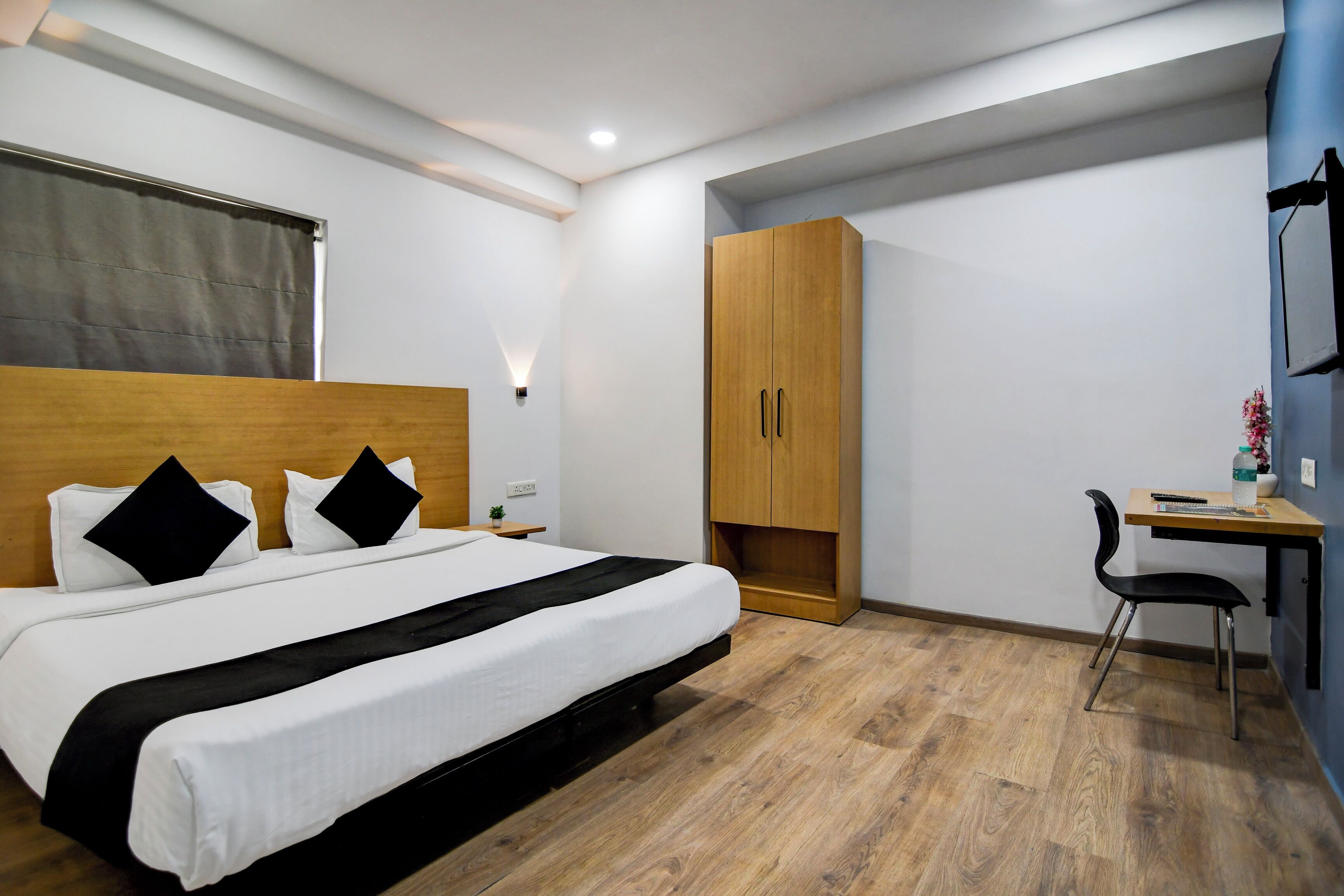 Een moderne hotelkamer met een groot bed, een houten garderobe, bureau en stoel.