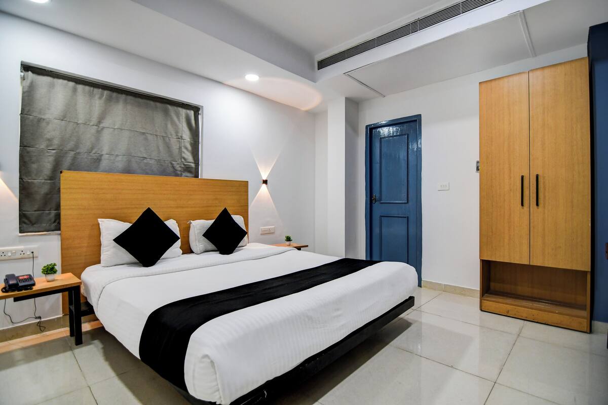 A neatly arranged bedroom with a bed, bedside tables, a wardrobe, and a blue door.