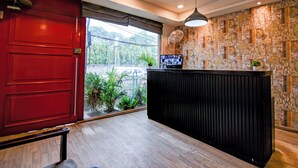 A reception area with a red door, a black reception desk, a television, and a patterned wall.