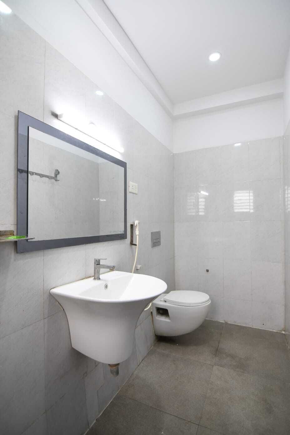 A bathroom with a white sink, a toilet, and a mirror.