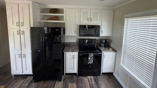 A compact kitchen with white cabinets, a black refrigerator, a microwave, a coffee maker, and a stove. - Cozy & quiet 2 bedroom country getaway, close to all the fun! (Elberta)