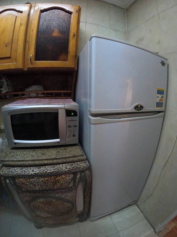 A compact kitchen with a microwave, refrigerator, and wooden cabinets. - Panoramic Sea view apartment in Alexandria (Alexandria Governorate)
