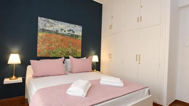 Un dormitorio con cama, dos lámparas de noche, un cuadro en la pared y un armario.