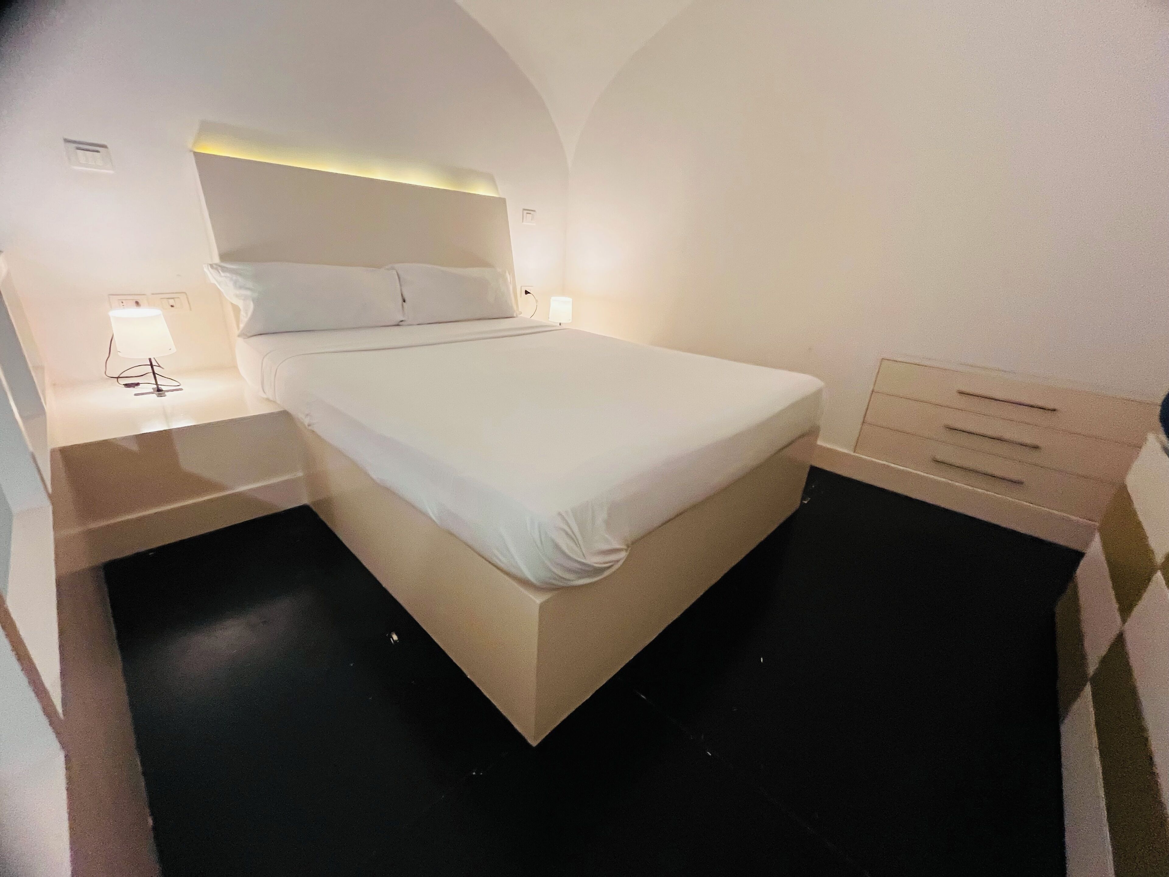 A modern hotel room with a large bed, bedside tables, and a built-in wardrobe.