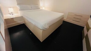 Una habitación de hotel moderna con una cama grande, mesitas de noche y un armario empotrado.