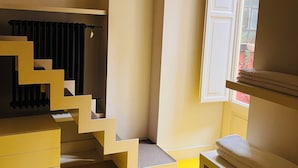 Una habitación con piso amarillo, puerta blanca y ventana con vista al exterior.
