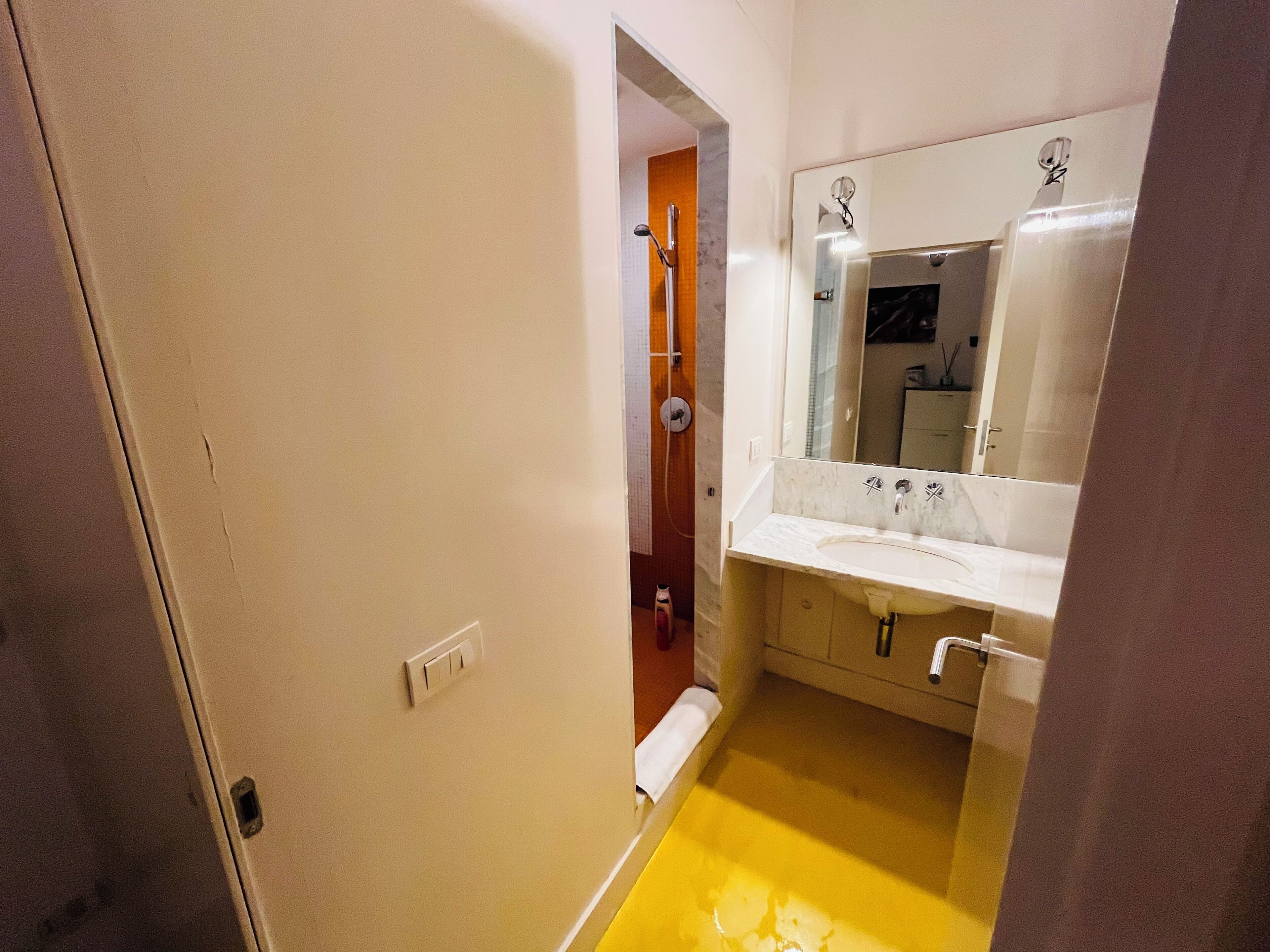 A bathroom with a white sink, mirror, and yellow floor.