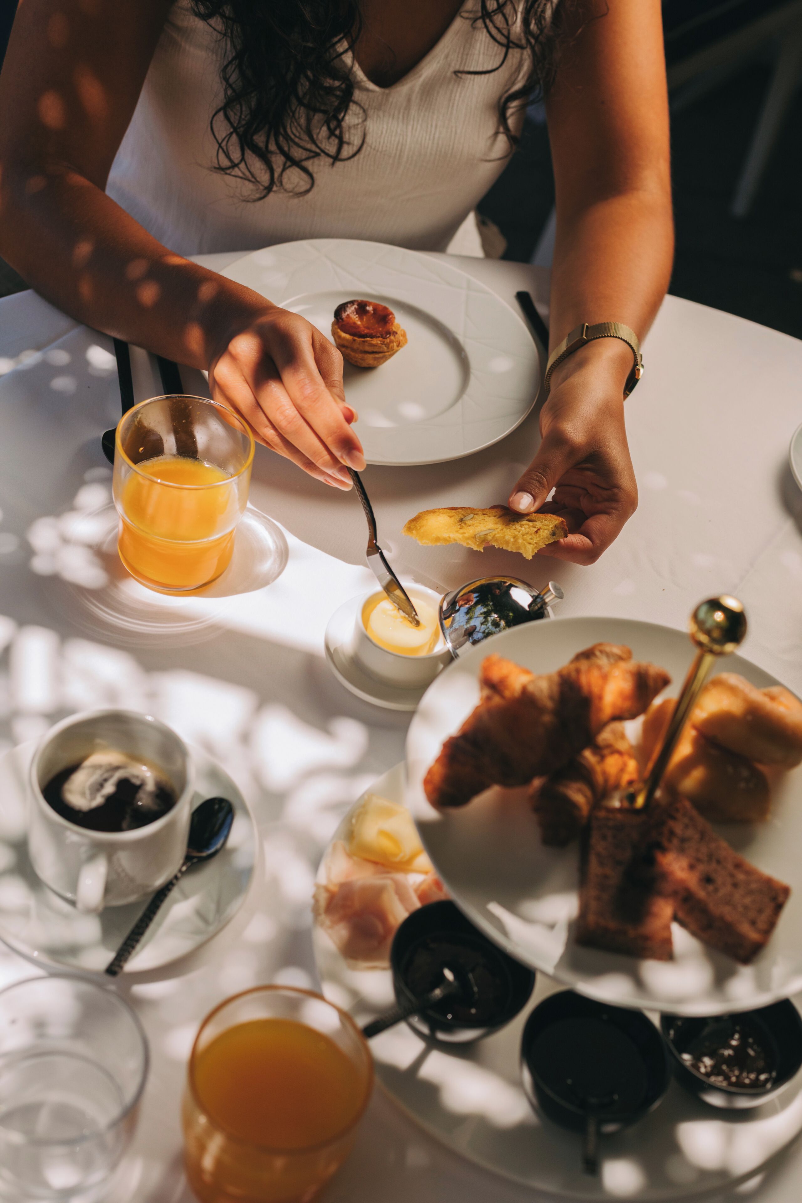 Una mesa de comedor con un plato de croissants, un vaso de jugo de naranja y una taza de té.