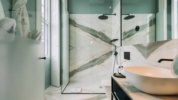 Un bagno moderno con cabina doccia in vetro, lavabo bianco e pannello di schienale in marmo.