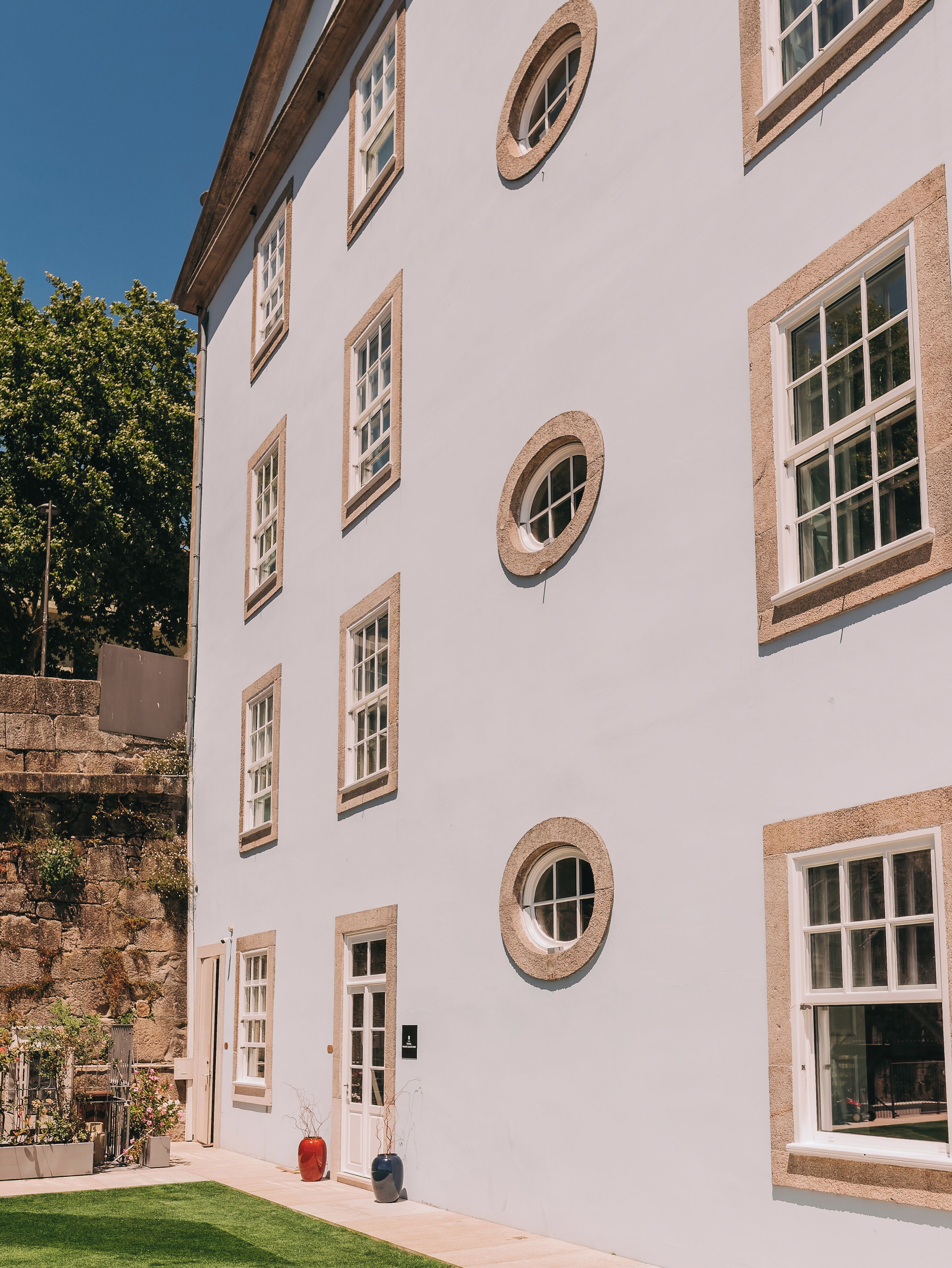 A multi-story building with multiple windows, a stone facade, and a well-maintained lawn.