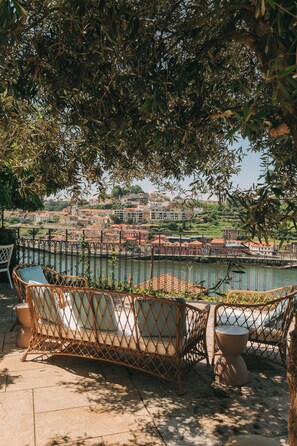 Outdoor seating with a view of a river and buildings in the background. - Torel Private Collection (Porto)