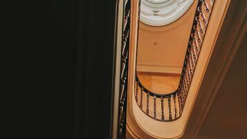 Una vista de una imponente escalera con un tragaluz circular y un piso de mármol.