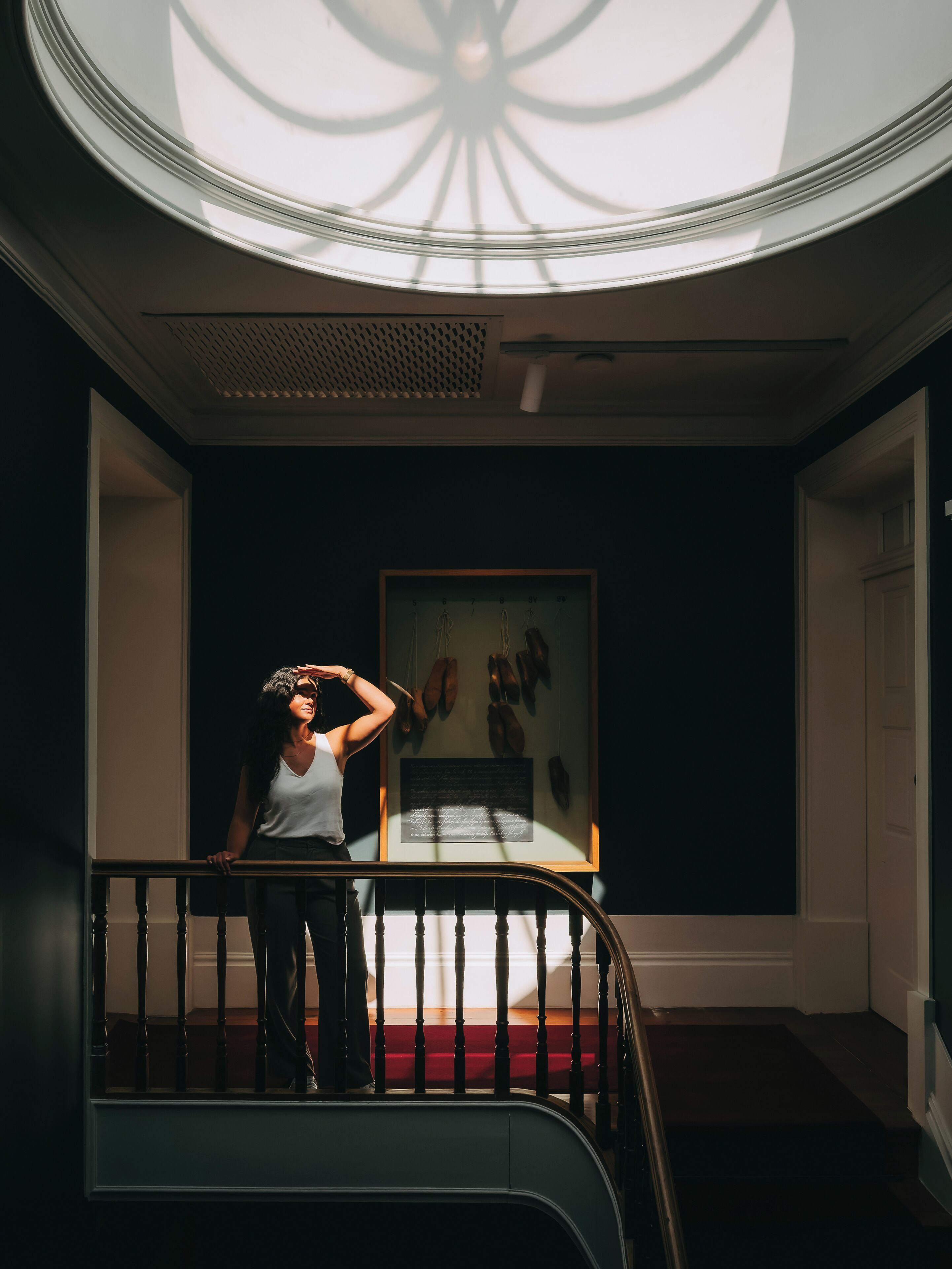 A person standing on a staircase with a framed artwork on the wall behind them.