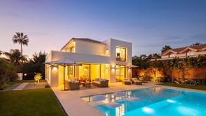 Een modern herenhuis met zwembad, terrasmeubels en een goed verlicht patio.