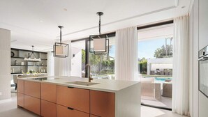 Een moderne keuken met een groot eiland, inbouwmeubels en hanglampen.