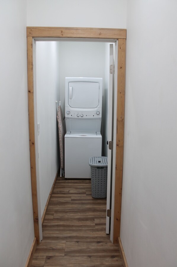 A laundry room with a washing machine and dryer, a wooden door frame, and a laundry basket.
