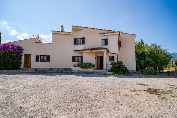 Une maison à deux étages avec une allée en gravier et un petit jardin.
