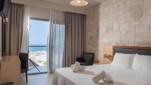 Ein Hotelzimmer mit Bett, Schreibtisch, Stuhl, Fernseher und Meerblick.