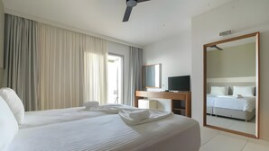 Una camera d'albergo con un letto grande, una scrivania, una televisione e uno specchio.
