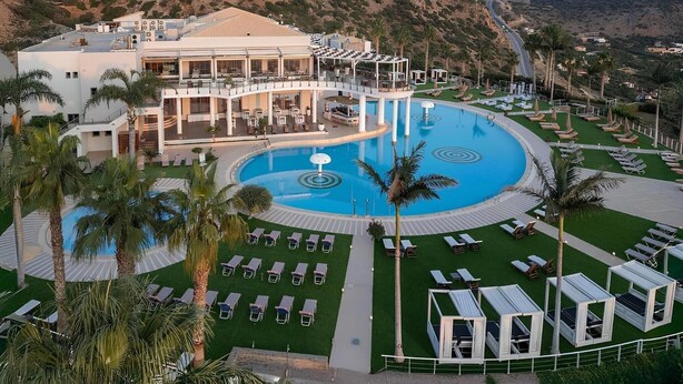A resort with a large central pool, sun loungers, and a multi-level building with outdoor seating. - Mini Villa with Pool View (Malia)