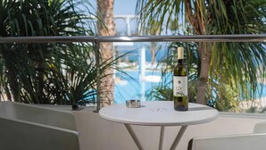 A balcony with a table, a bottle of wine, and a metal ashtray. - Mini Villa with Pool View (Malia)