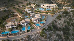 Resort com vários edifícios, piscinas e uma estrada sinuosa.