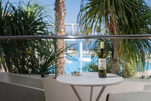 Un balcon avec une table, une bouteille de vin et un cendrier en métal.