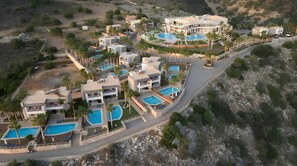 Een resort met verschillende zwembaden, moderne architectuur en een glooiend landschap.