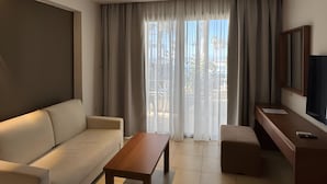 A modern living room with a sofa, a coffee table, a TV, and a ceiling fan. - Villa 'One Bedroom Villa with Pool View' with Wi-Fi and Air Conditioning (Malia)