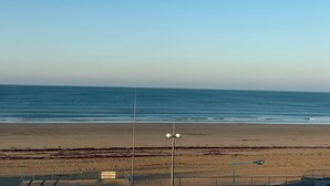 Uma praia com céu claro, uma placa indicando um correio e um poste de luz.