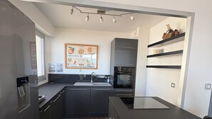 Cozinha moderna com ilha central, eletrodomésticos embutidos e piso de madeira.