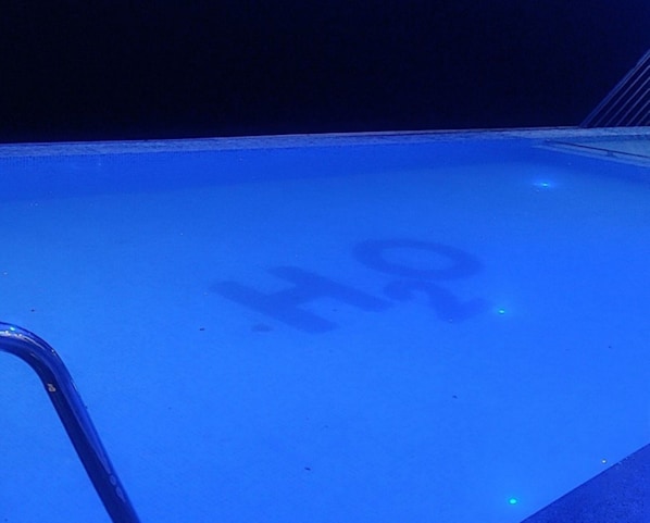 Una piscina con un logotipo visible y una escalera metálica.